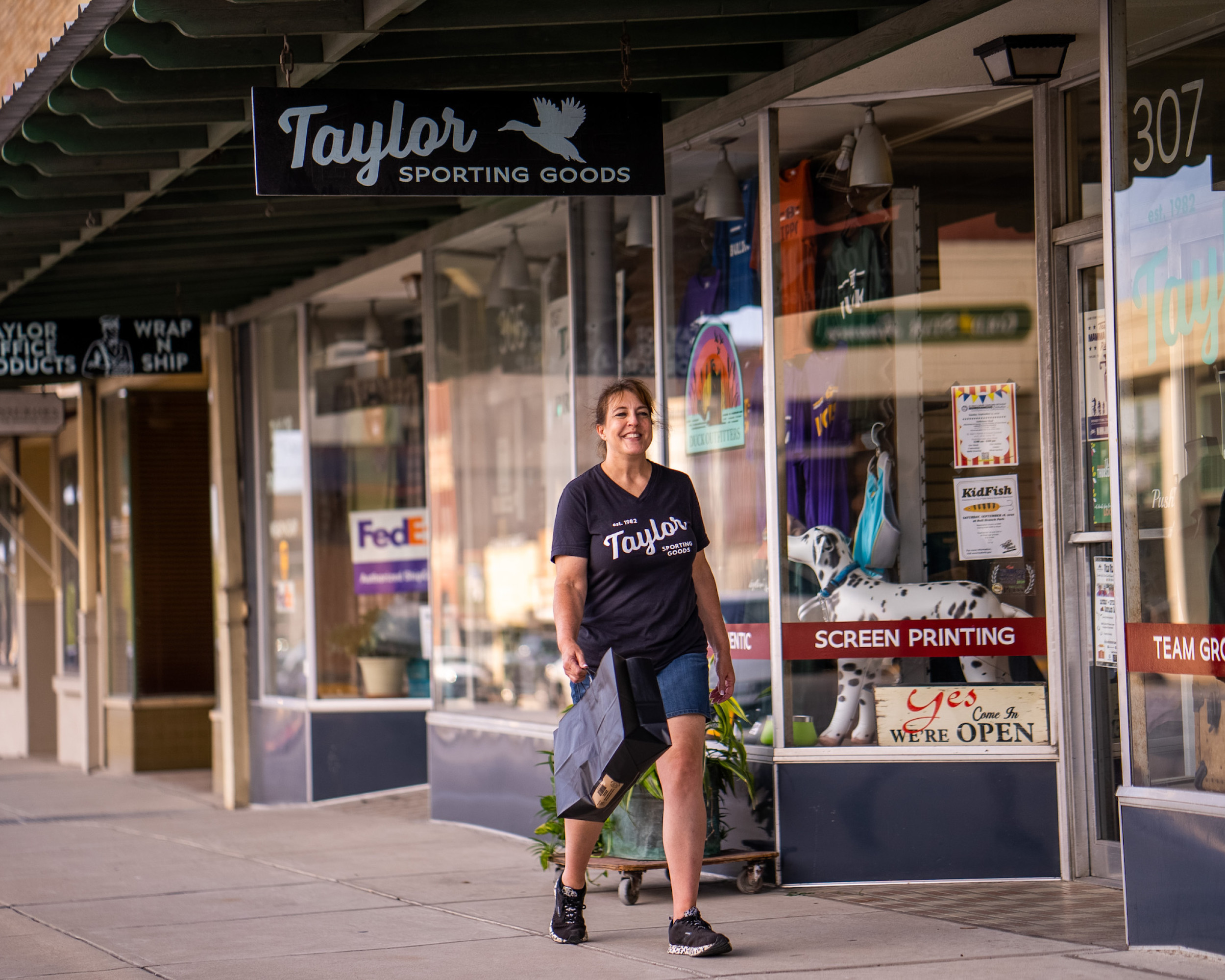 A woman walking in front of the Taylor Sporting Goods store